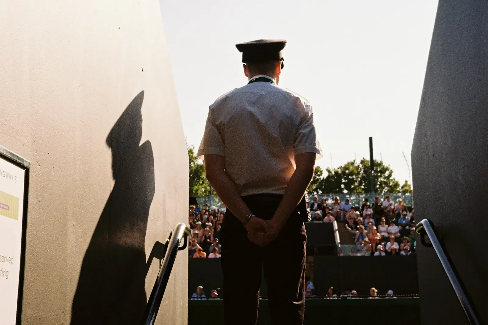 Steward en uniforme face aux tribunes d’une enceinte sportive